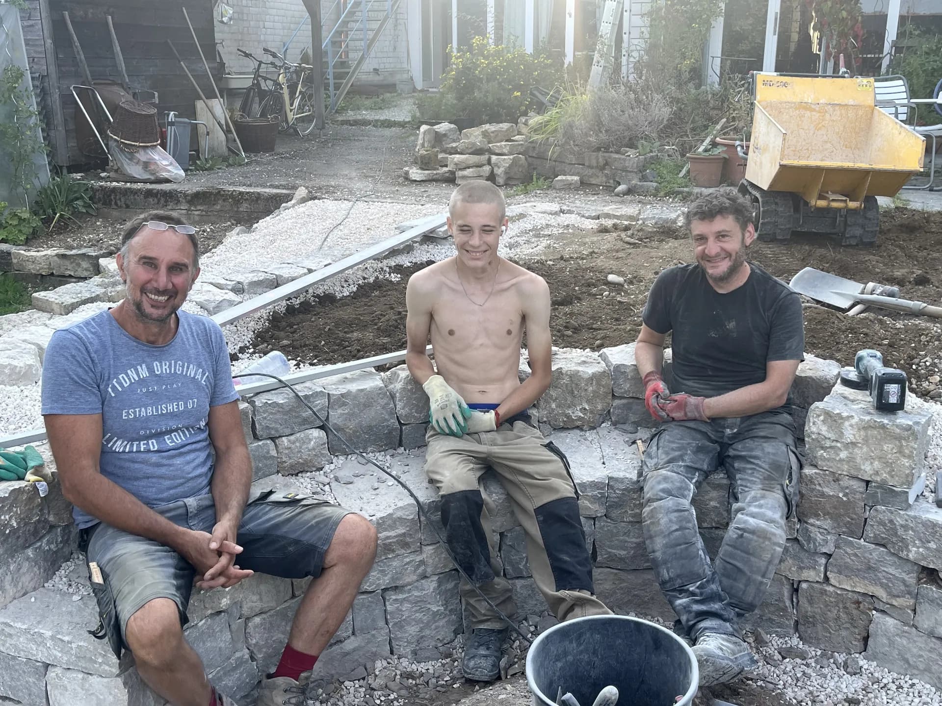 Gartenbau-Team vor fertig gestellter Trockenmauer